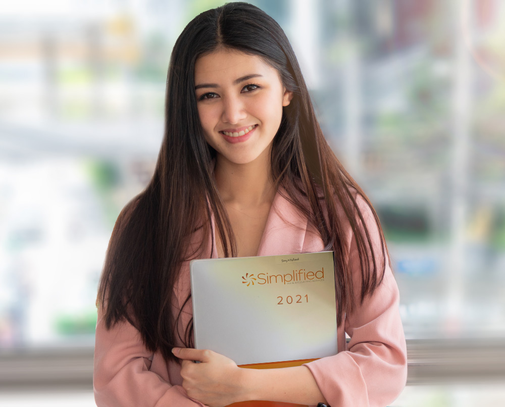 A female standing with a Simplfied Tax folder in her hand.